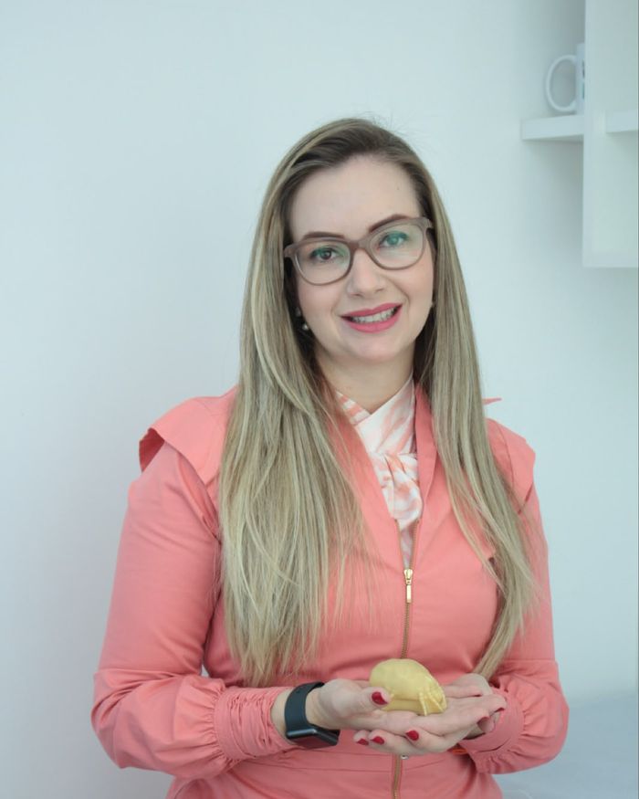 Dra. Gabriela segurando um modelo anatômico no consultório