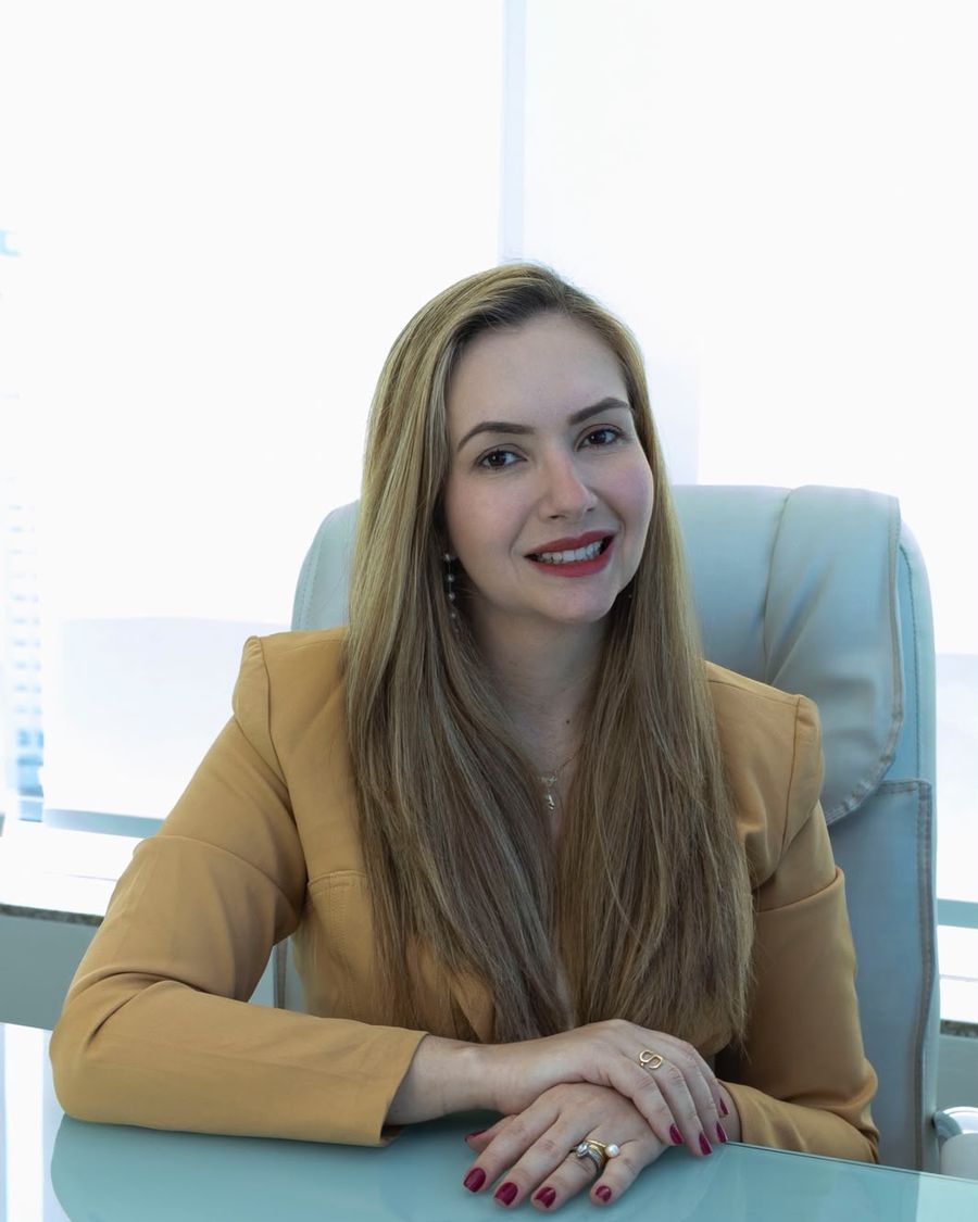 Dra. Gabriela Dourado sentada à mesa no consultório